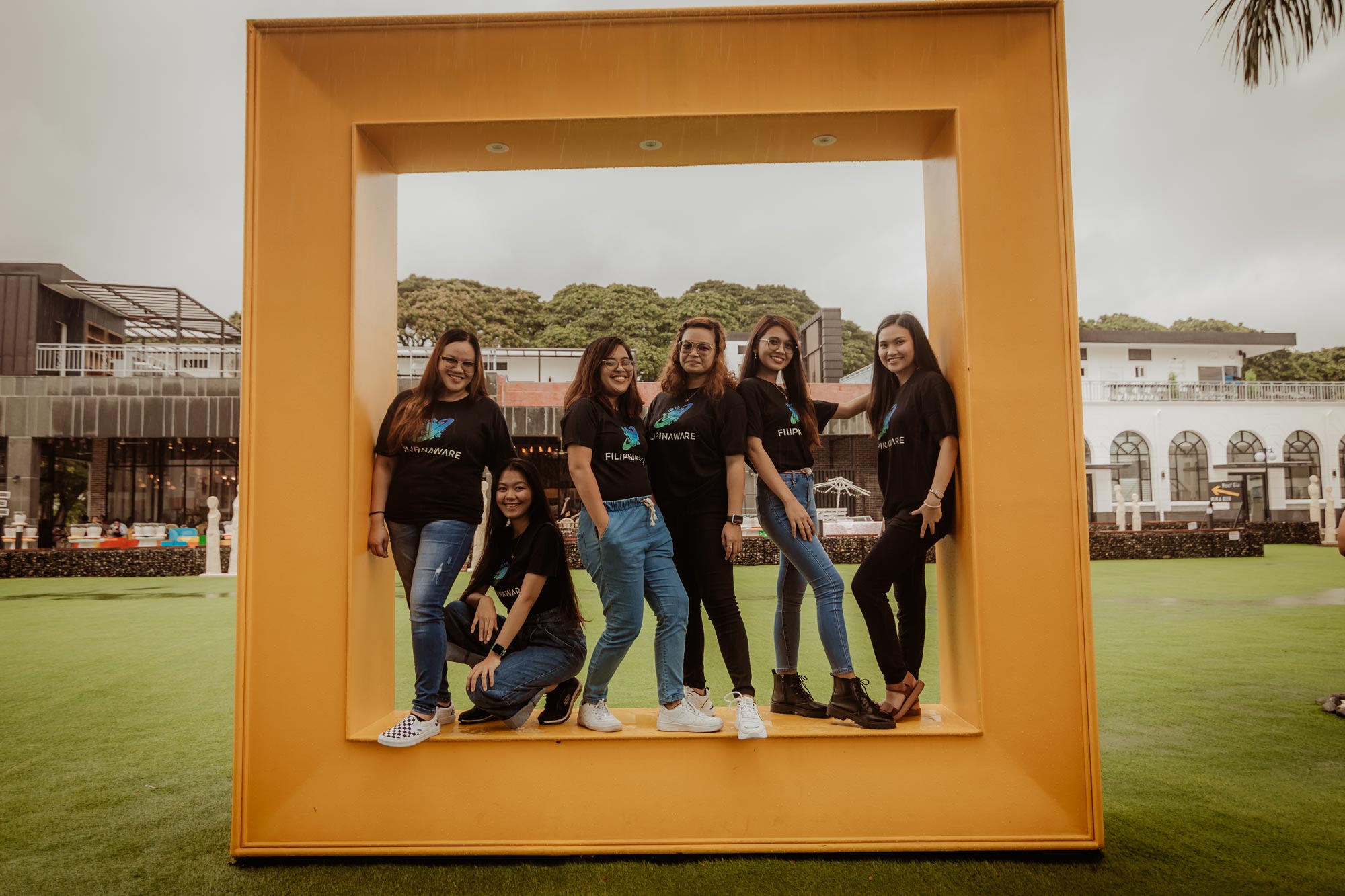 A group photo of 6 women employees posing inside a square platform structure